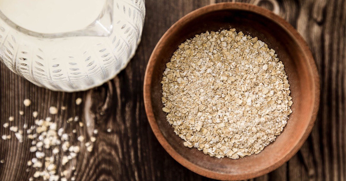 Wooden bowl of oats with milk jug on rustic table. Ideal for health-focused breakfast imagery.