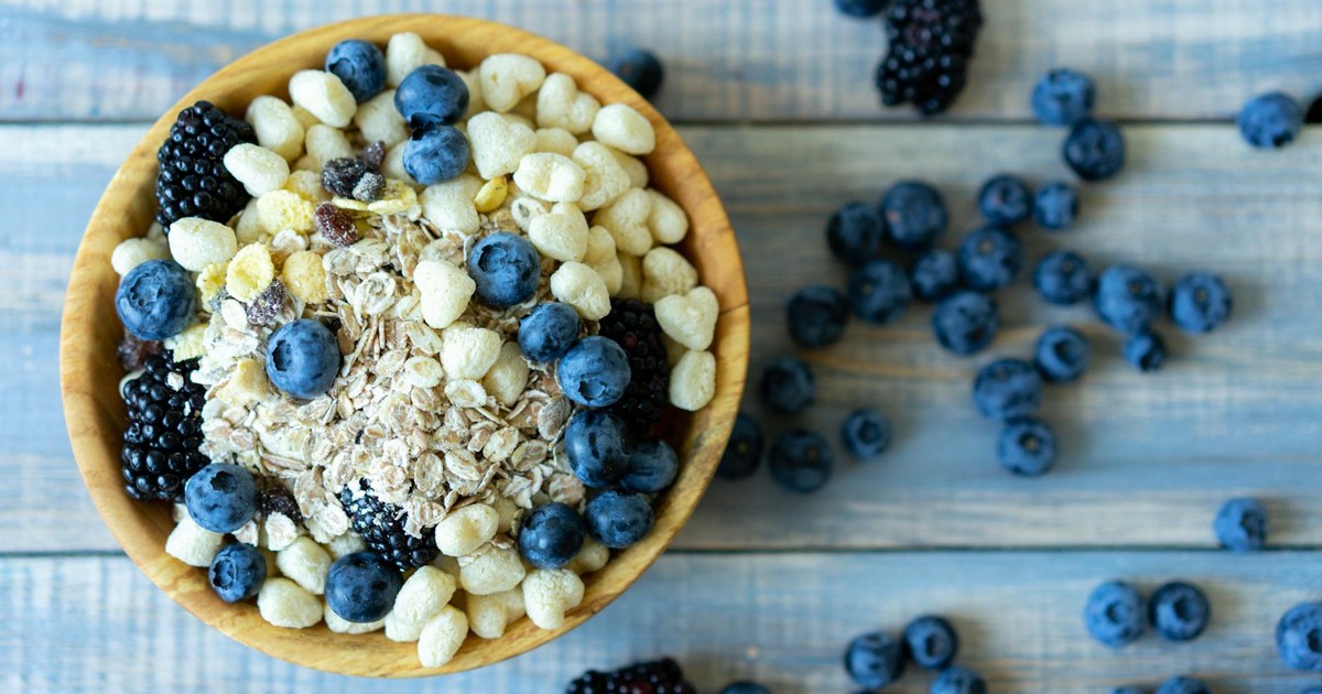 Top view of a nutritious breakfast bowl with blueberries, blackberries, and cereal on a rustic wooden table.
