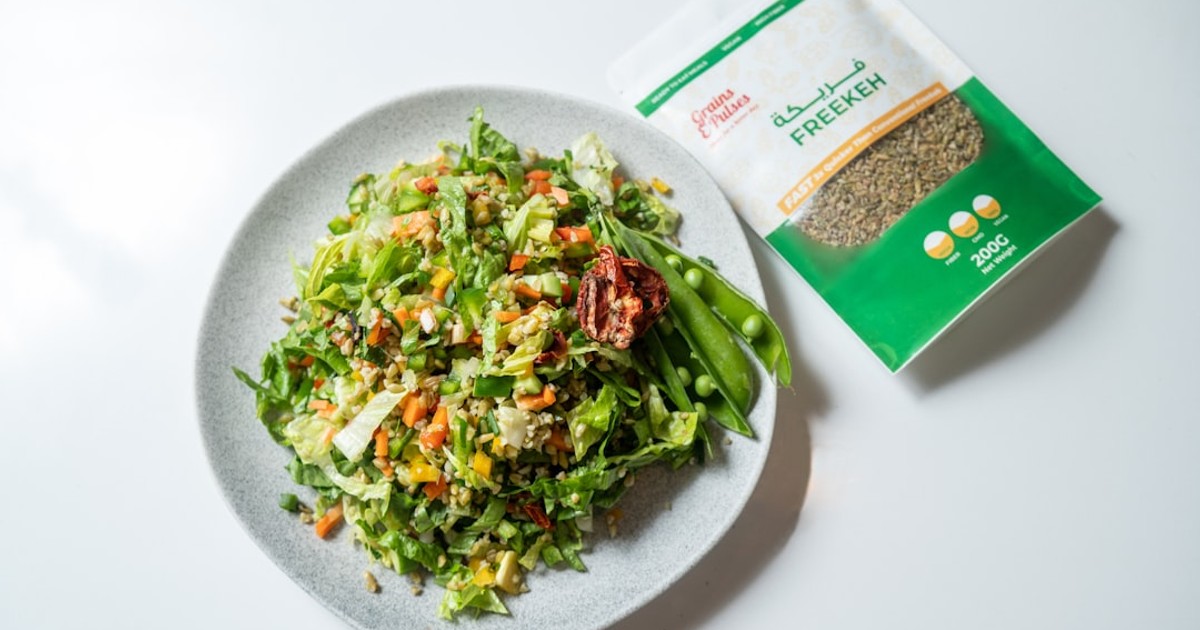 a white plate topped with a salad next to a bag of seeds