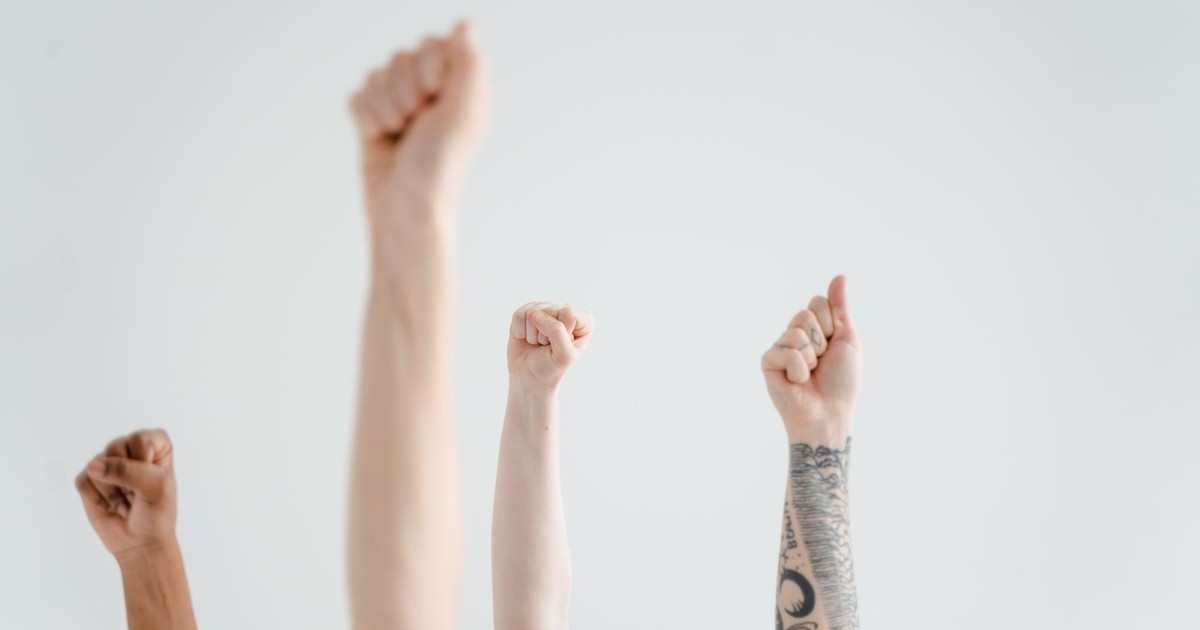 Hands raised in solidarity, symbolizing unity and protest against a plain background.