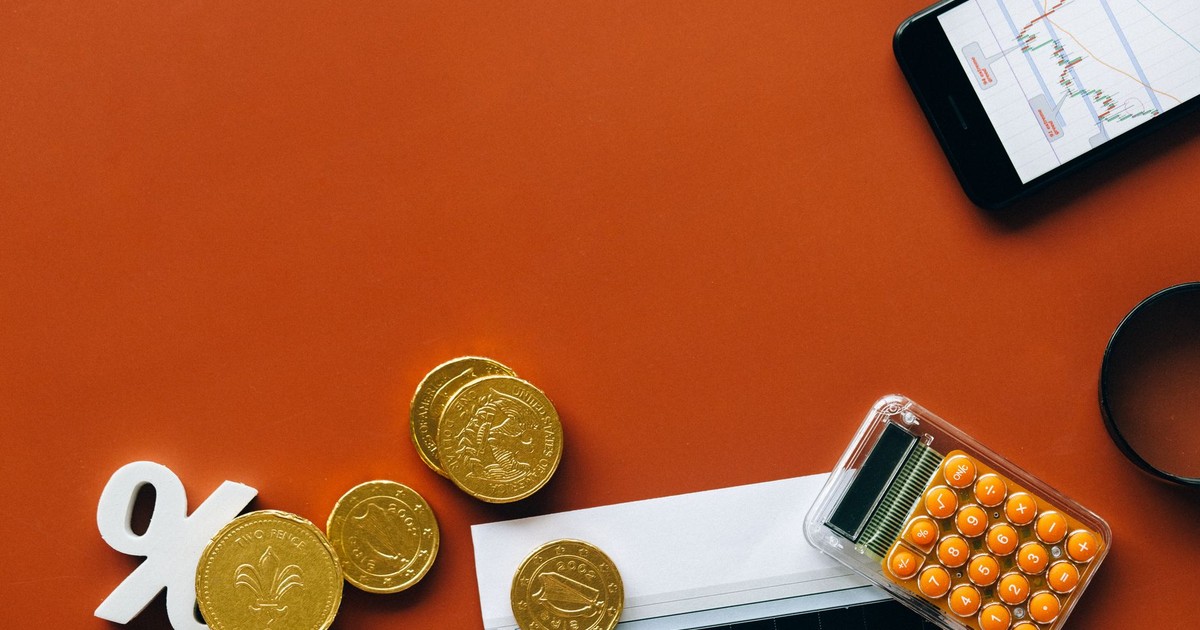 Flat lay showing coins, calculator, and charts on a red background for financial analysis and business concepts.
