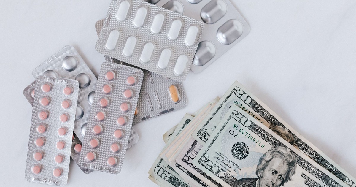 Top view of different blisters of medications and pills composed with heap of paper money