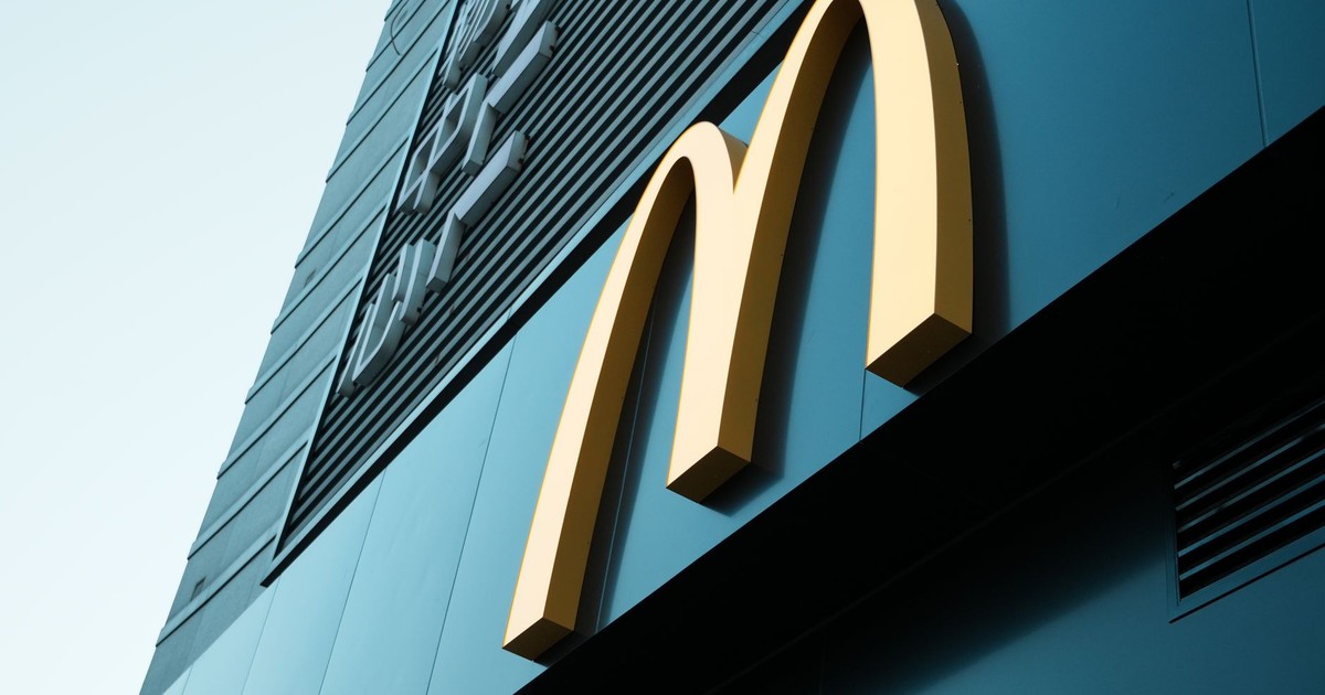 Large fast food restaurant golden arch sign on a modern building facade.