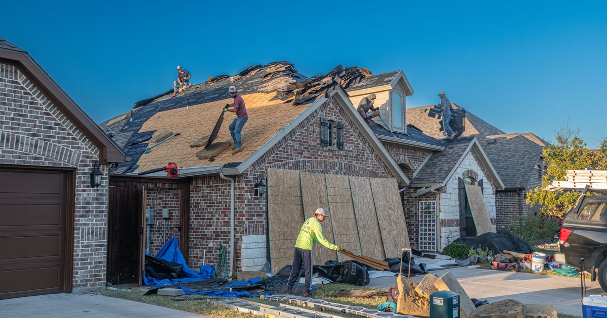Workers engage in roof replacement on a brick house in Fort Worth, Texas.