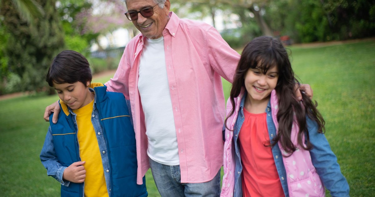 Happy grandfather bonding with grandchildren in a lush park, enjoying a joyful day outdoors.