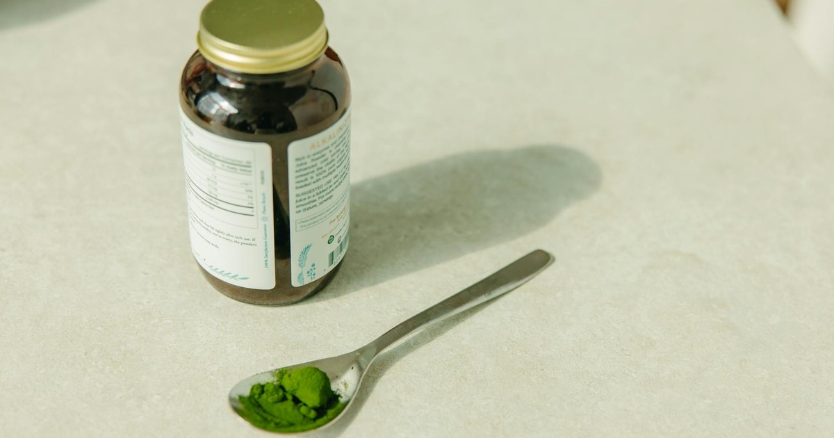 Close-up of a jar and a spoon with green powder, ideal for healthcare and wellness themes.