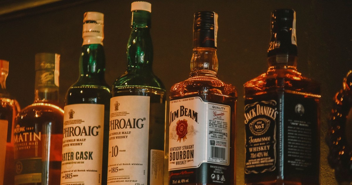 A selection of premium whiskey brands elegantly arranged on a dimly lit display shelf.
