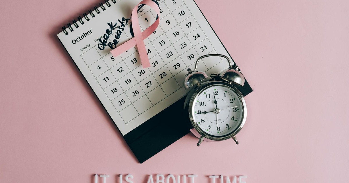 Calendar with pink ribbon, an alarm clock, and the text "Check breasts" signifies Breast Cancer Awareness.