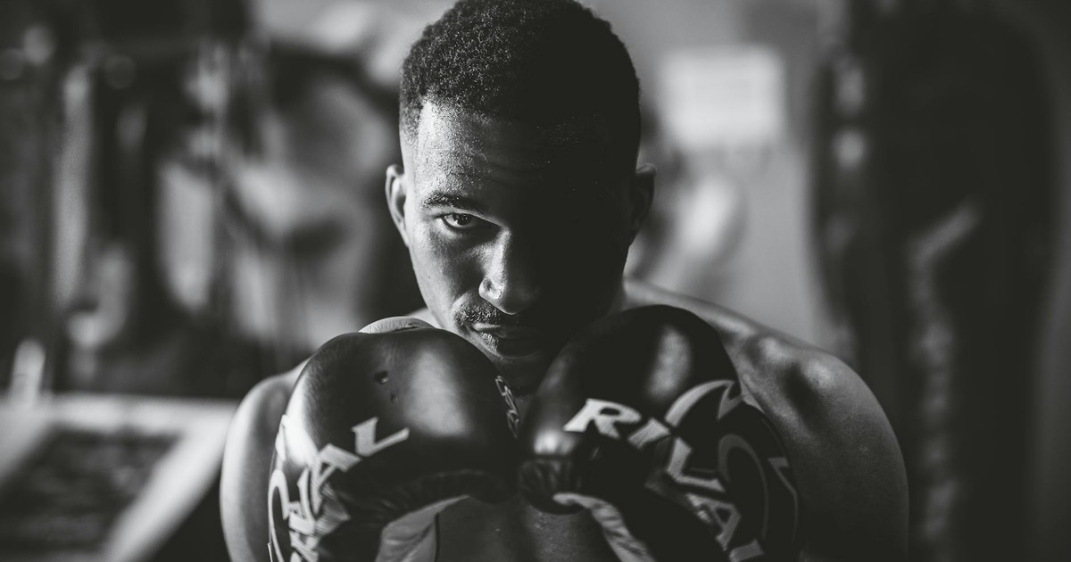 Dramatic black and white portrait of a focused boxer in a gym setting, highlighting strength and determination.