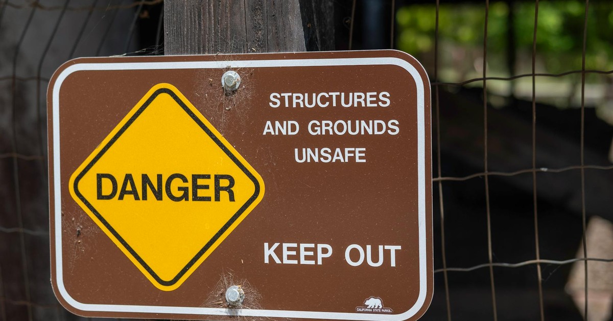 Danger sign warning about unsafe structures and grounds with keep out notice.