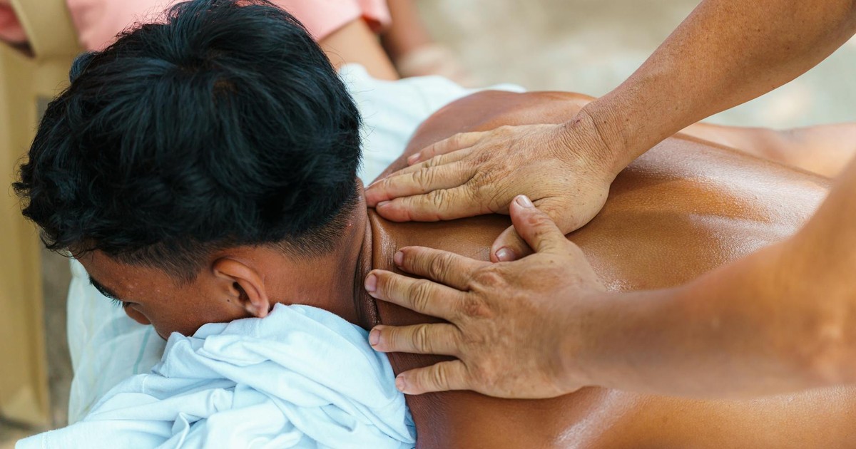 Close-up of a relaxing outdoor massage session with focus on hands and back.