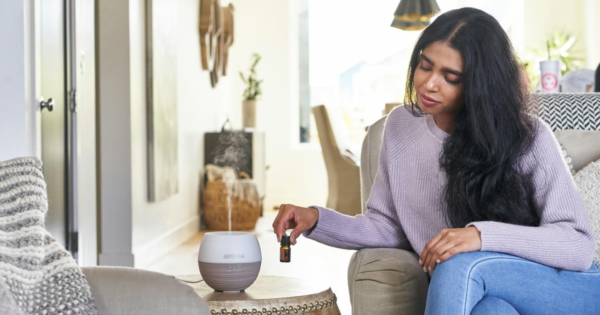 A woman in a cozy setting using an essential oil diffuser for relaxation and wellness.