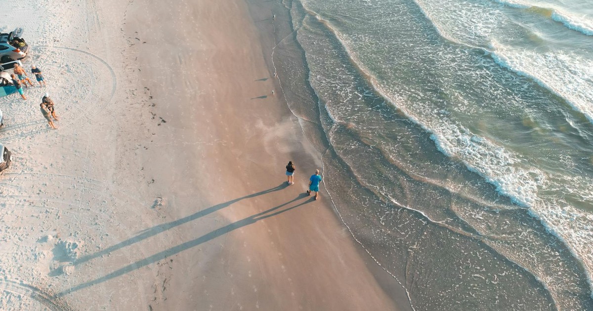 Serene aerial shot of Padre Island beach with waves and people walking at sunset.