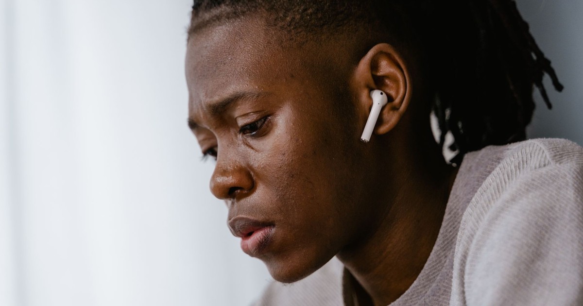 Side profile of a focused individual wearing wireless earphones, conveying introspection.