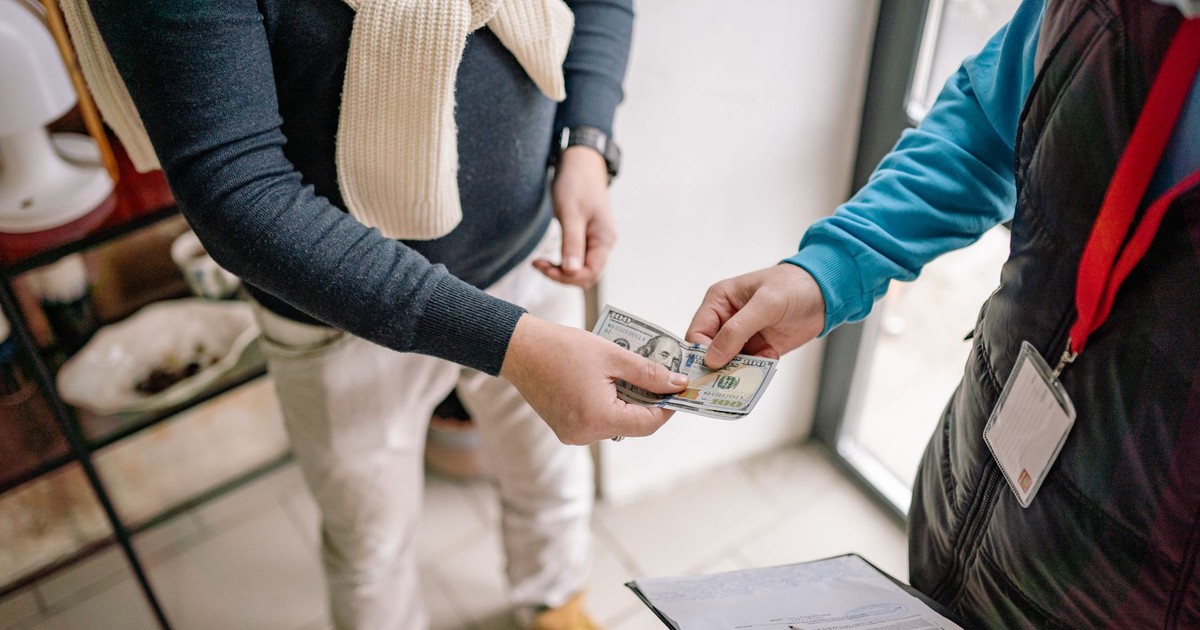 Close-up of hands exchanging cash during a transaction indoors, highlighting payment details.