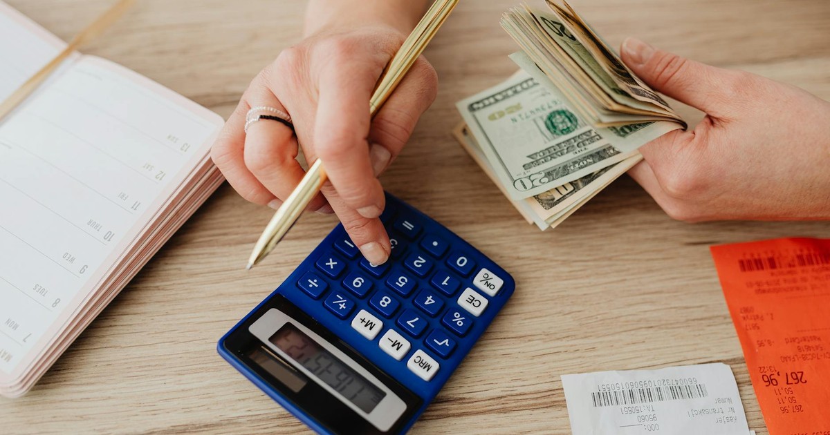 Hands handling cash and calculator for budget planning. Modern financial scene.