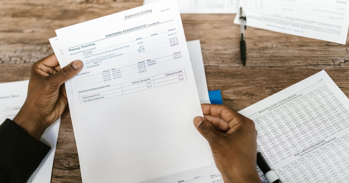 Hands holding financial papers for tax preparation and analysis.