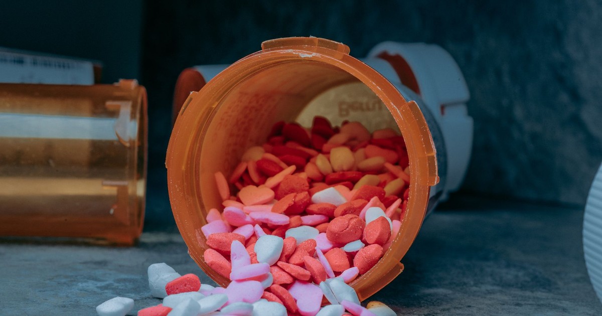 Close-up of heart-shaped pills spilling from a prescription bottle on a surface.