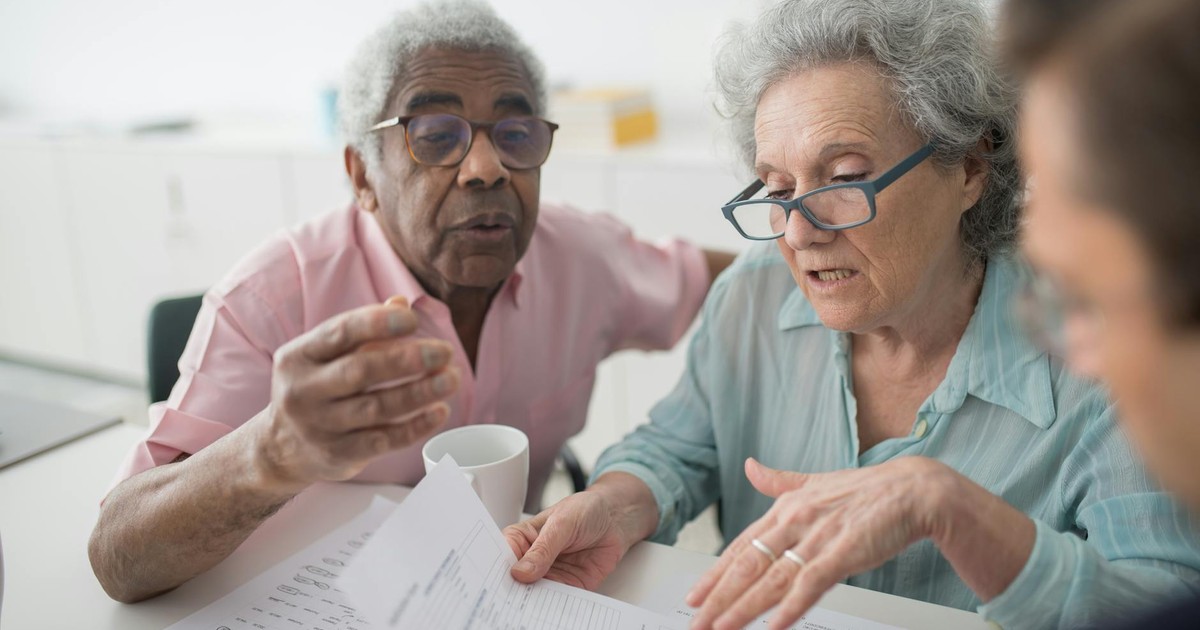 Elderly couple discussing financial documents with a consultant in an office setting.