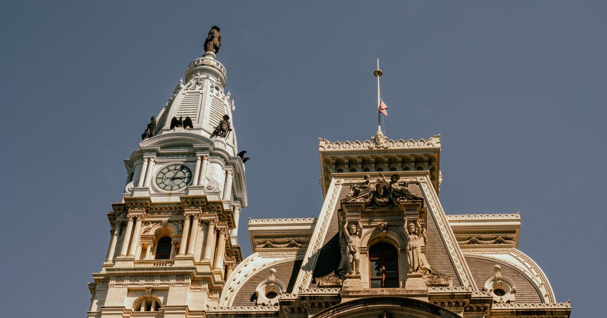 Close-up perspective of the iconic Philadelphia City Hall with its grand clock tower against a clear sky.