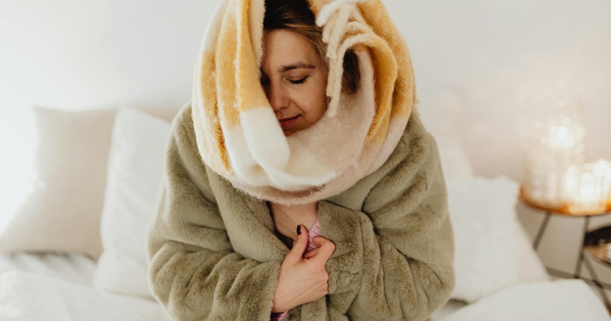 Woman wrapped in a fluffy blanket enjoying a cozy moment at home.