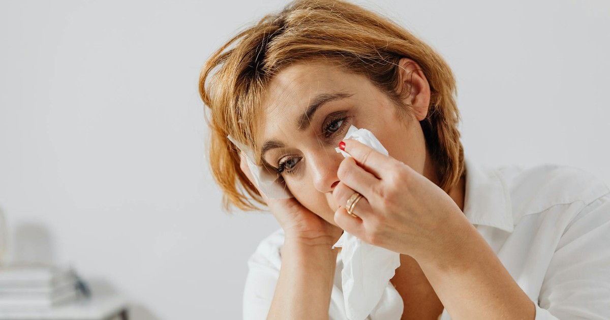 Portrait of woman holding tissue, expressing emotion, wiping tears.