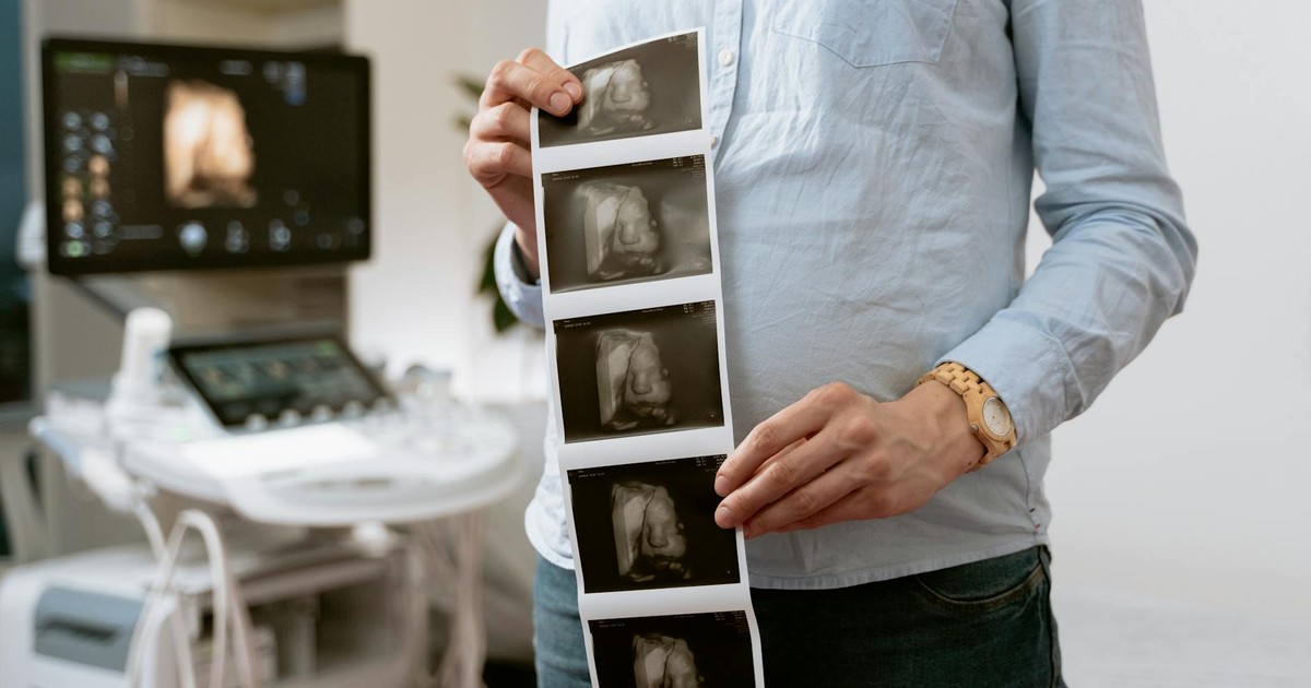 A person holding ultrasound images in a medical clinic, showcasing pregnancy monitoring.