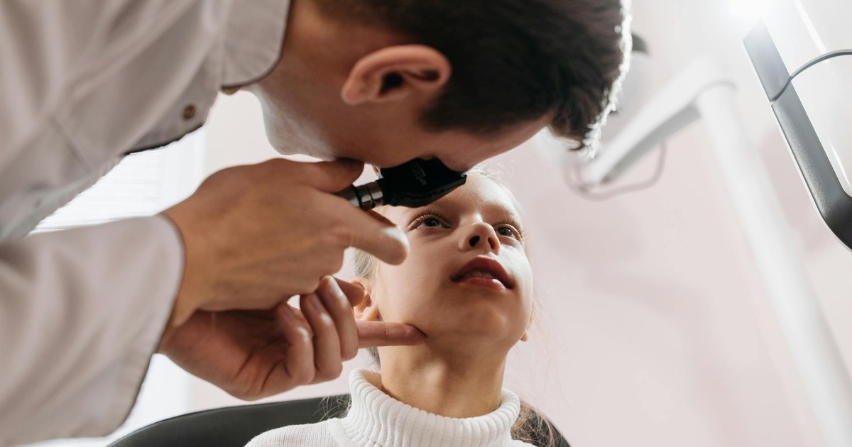 Doctor performs an eye examination on a young girl in a clinic setting, showcasing pediatric healthcare.