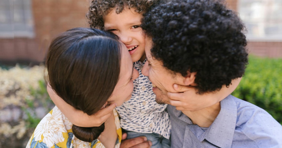 Happy family sharing an affectionate hug outdoors in a vibrant garden.