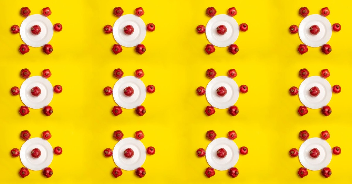 A vibrant pattern of red apples arranged on white plates against a bright yellow background.