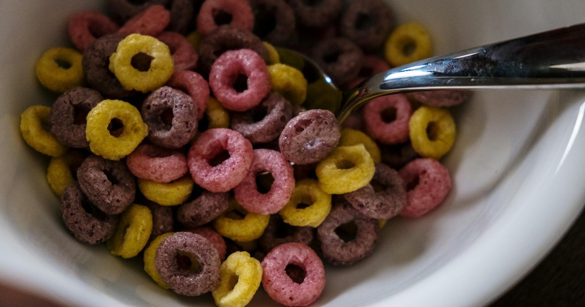 Vibrant fruity cereal rings in a white bowl with a spoon, emphasizing breakfast theme.