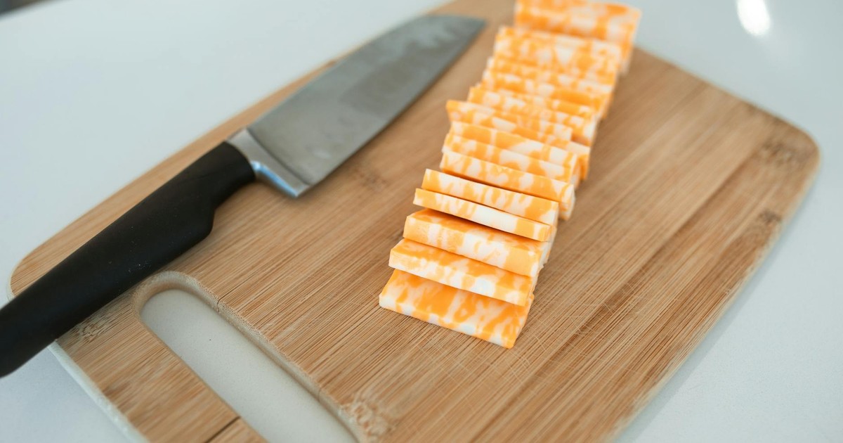 Sliced colby-jack cheese neatly arranged on a bamboo cutting board with a kitchen knife.