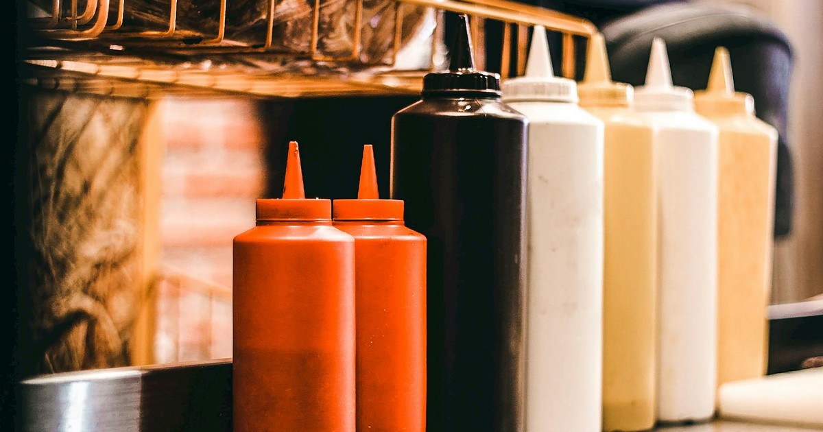 Vibrant condiment bottles lined up in a restaurant kitchen, showcasing various sauces.