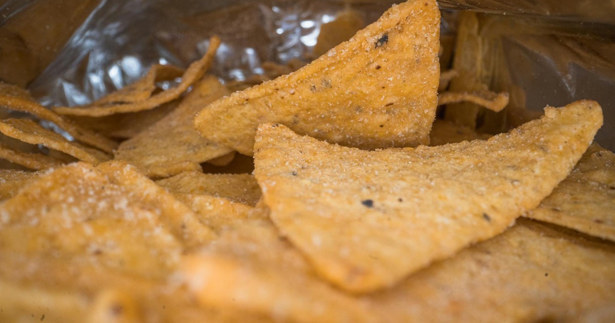 Macro shot of salted tortilla chips inside an open bag, showcasing texture.