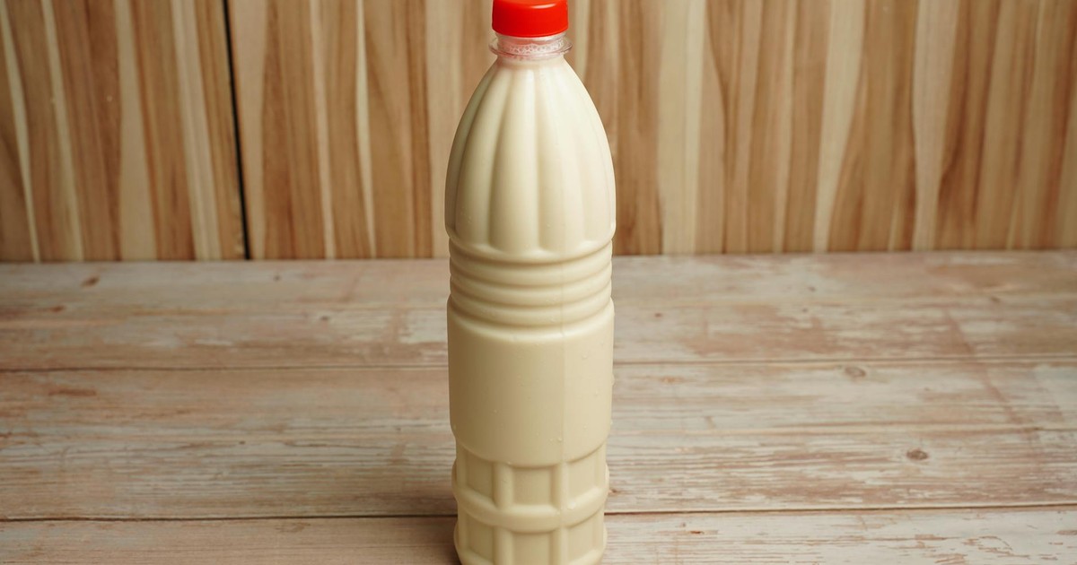 Close-up of a plastic milk bottle with a red cap on a rustic wooden table with copy space.