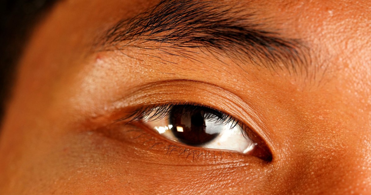 A detailed close-up of a human eye showcasing the texture and color of the skin and eyelashes.