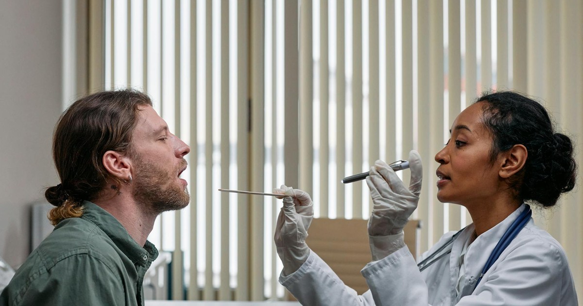 A doctor examining a patient's throat in a clinical setting, highlighting professional healthcare.