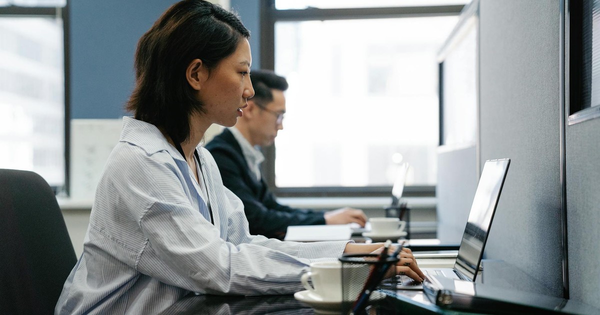 Two professionals working diligently on laptops in a modern office setup, capturing productivity and teamwork.