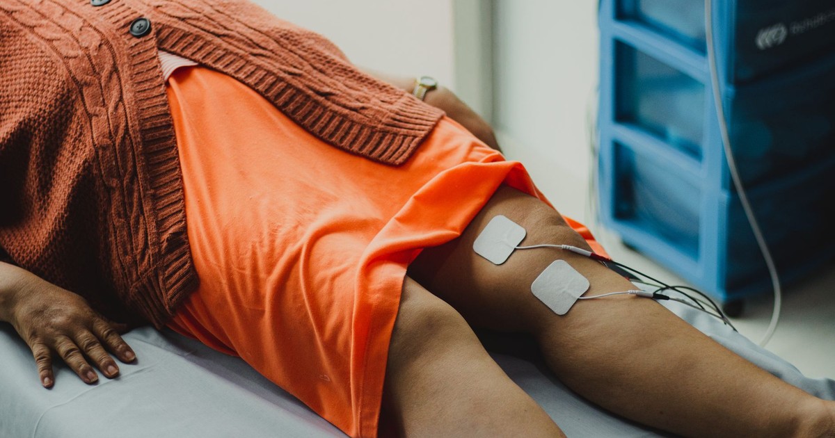 Close-up of a woman's legs during an electrical therapy session in a hospital setting.