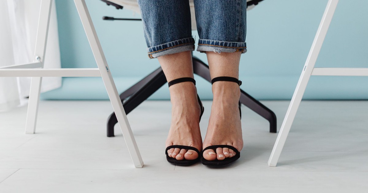 Stylish close-up of a woman wearing black high heels, jeans, and sitting on a chair.