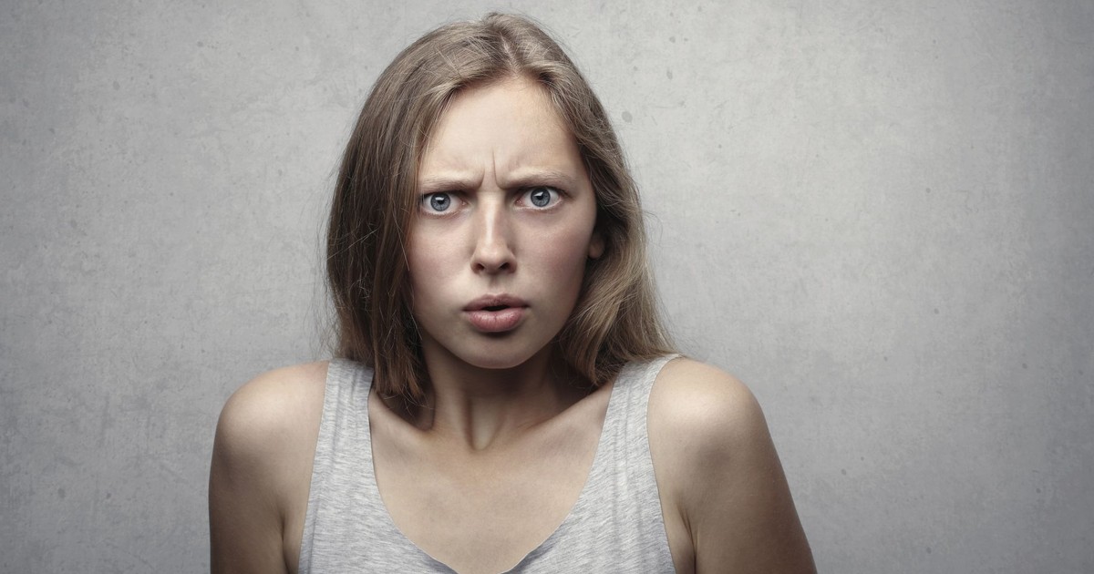 Close-up portrait of a pensive woman with a confused facial expression indoors.