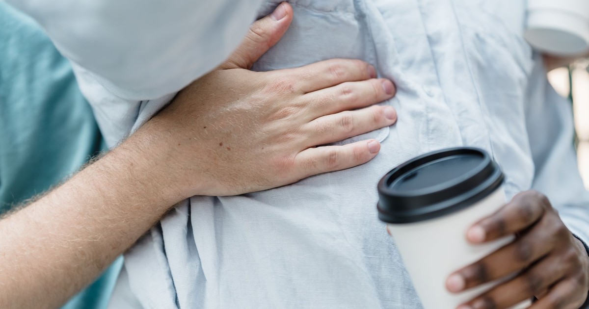 Close-up image of an interracial couple embracing while holding coffee cups, expressing warmth and connection.