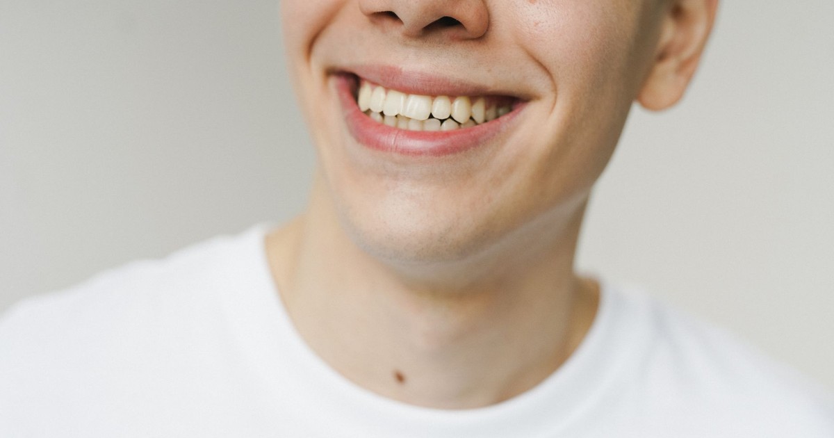 A close-up shot of a young man smiling, highlighting his teeth and expression.