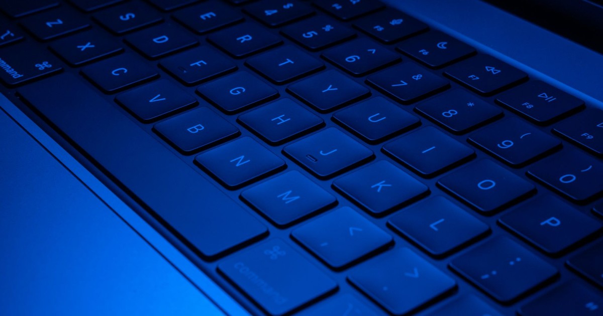 Close-up image of a laptop keyboard illuminated with blue light, showcasing modern technology design.