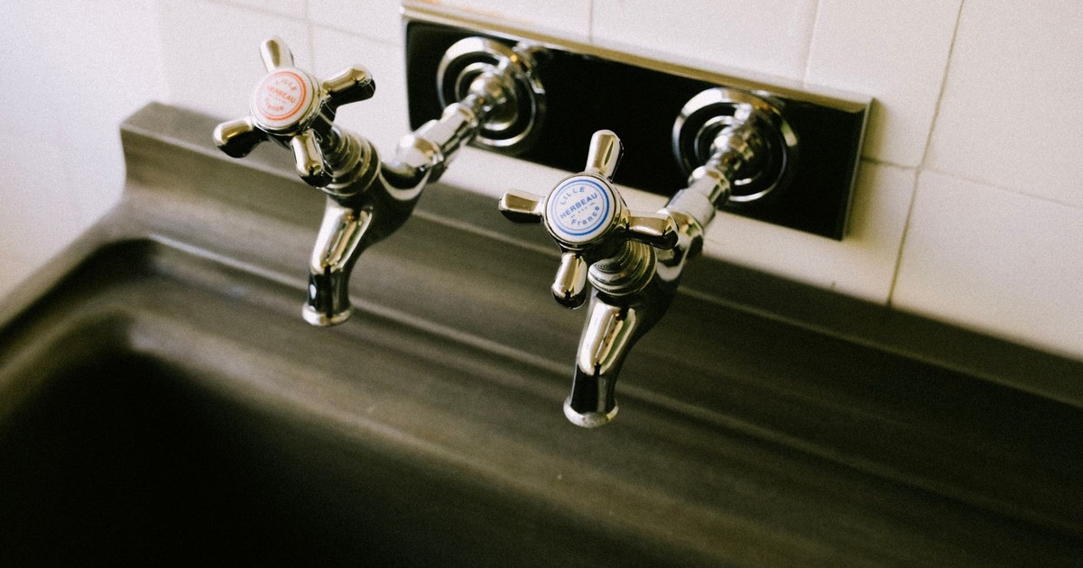 Detailed view of chrome sink faucets with classic hot and cold labels in a kitchen setting.