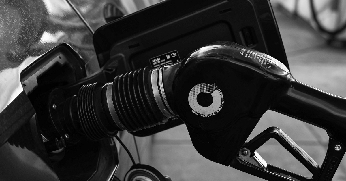 Detailed close-up of a refueling nozzle in monochrome at a gas station, highlighting the petrol filling process.