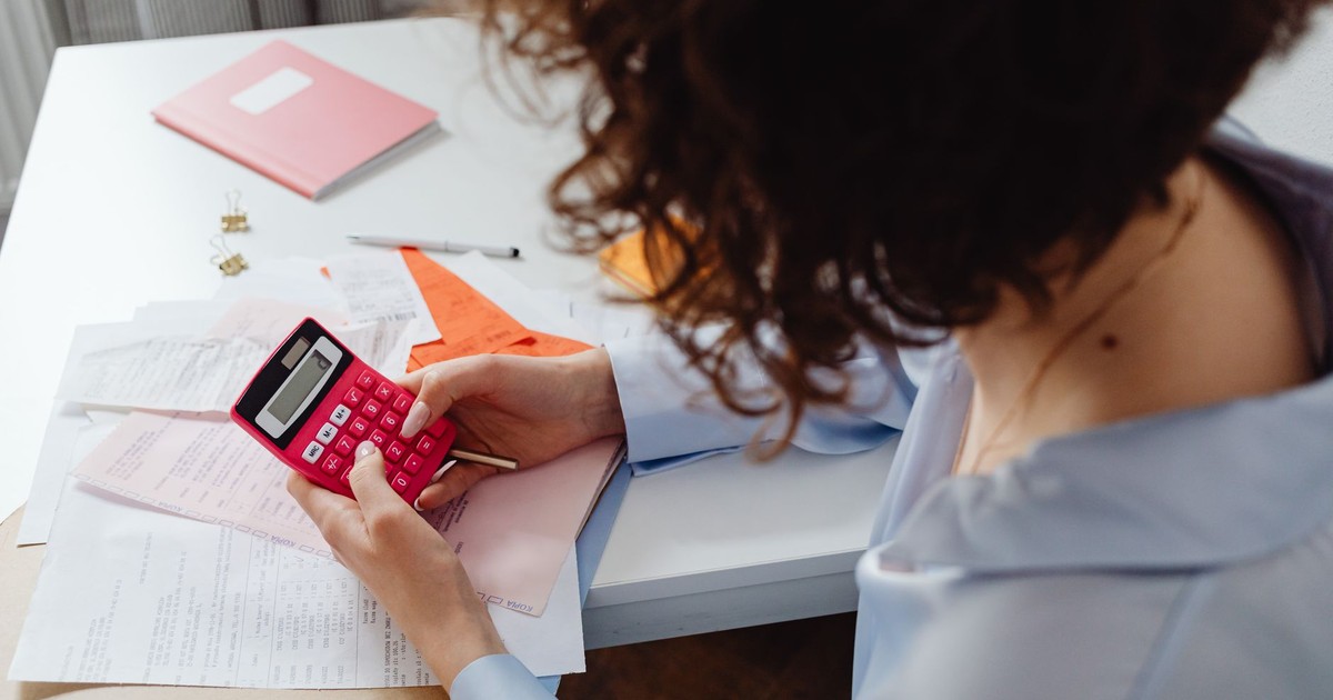 Woman calculating expenses with documents and calculator at work desk.