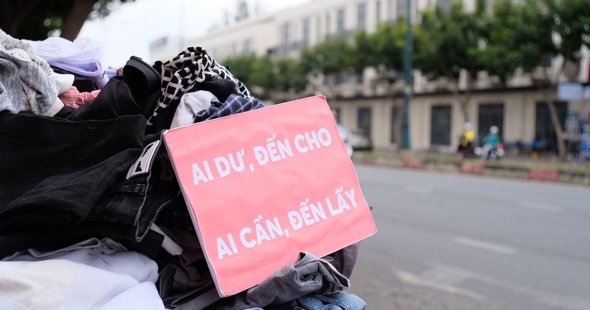 Clothes donation on city street with sign offering free items to those in need.