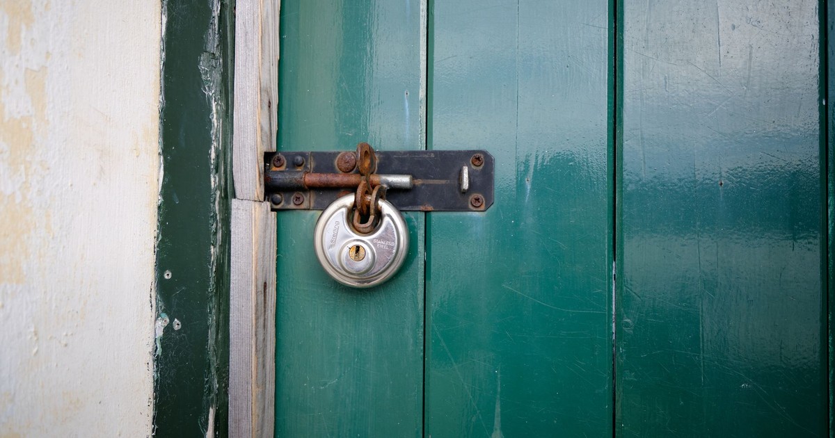 Close-up of a locked green wooden door with a metal padlock in Keswick, England.