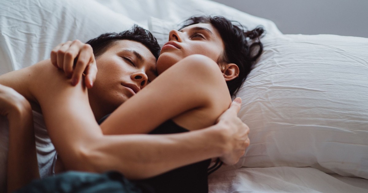A tender moment of an affectionate couple embracing in bed, capturing warmth and intimacy.